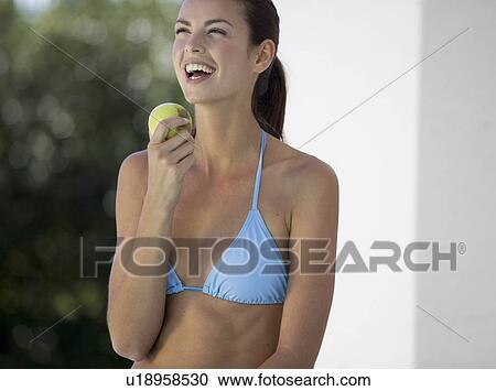 A woman in a bikini eating an apple View Large Photo Image Stock Image - A woman in a bikini eating an apple. Fotosearch