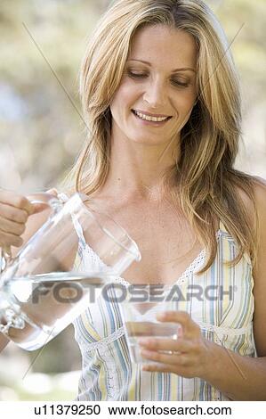 Woman pouring a glass of water View Large Photo Image Stock Image - Woman pouring a glass of water. Fotosearch