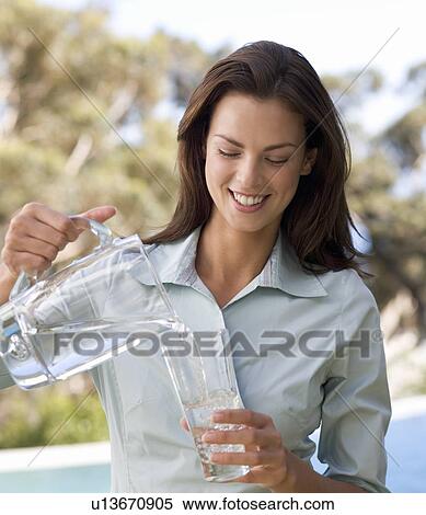 Woman pouring a glass of water View Large Photo Image Stock Photography - Woman pouring a glass of water. Fotosearch