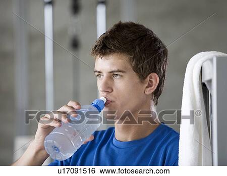 Stock Photograph - A young man drinking a bottle of water. Fotosearch