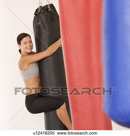 Stock Photography - A young woman hugging a punch bag. Fotosearch