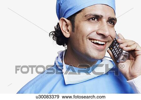 Close-up of a male doctor wearing surgical scrubs and talking on a mobile phone View Large Photo Image Stock Photo - Close-up of a male doctor wearing surgical scrubs and talking on a mobile phone. Fotosearch