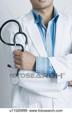 Mid section view of a male doctor holding a stethoscope View Large Photo Image Stock Photo - Mid section view of a male doctor holding a stethoscope. Fotosearch