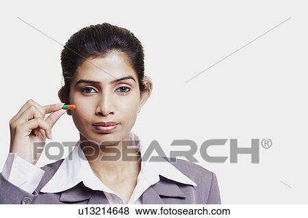 Stock Photo - Portrait of a businesswoman holding a capsule. Fotosearch