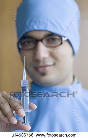 Stock Photograph - Portrait of a surgeon holding a syringe. Fotosearch