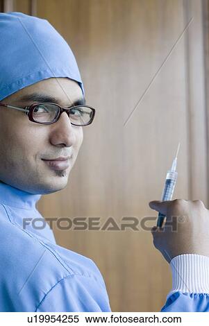 Stock Photography - Portrait of a surgeon holding a syringe. Fotosearch