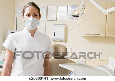 Stock Image - Dental assistant in exam room with mask on. Fotosearch