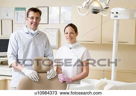 Dentist and assistant in exam room smiling View Large Photo Image Stock Image - Dentist and assistant in exam room smiling. Fotosearch