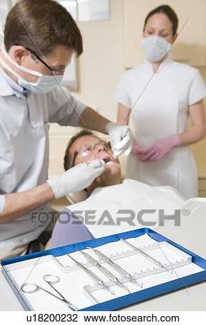 Dentist and assistant in exam room with man in chair View Large Photo Image Stock Image - Dentist and assistant in exam room with man in chair. Fotosearch