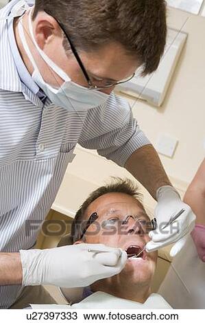 Dentist and assistant in exam room with man in chair View Large Photo Image Stock Image - Dentist and assistant in exam room with man in chair. Fotosearch