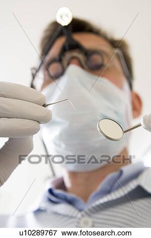 Dentist holding pick and mirror View Large Photo Image Stock Photo - Dentist holding pick and mirror. Fotosearch