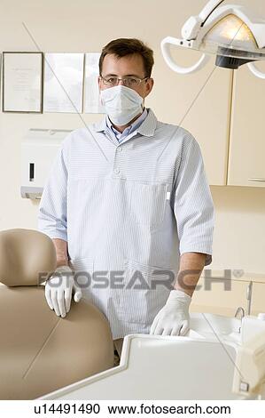 Stock Image - Dentist in exam room with mask on. Fotosearch