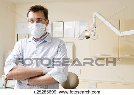 Stock Photo - Dentist in exam room with mask on. Fotosearch