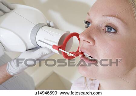 Stock Photo - Dentist in exam room with woman in chair. Fotosearch