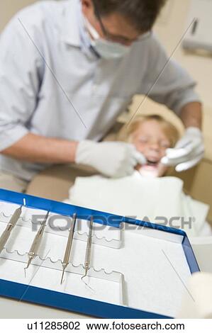 Stock Image - Dentist in exam room with young boy in chair. Fotosearch