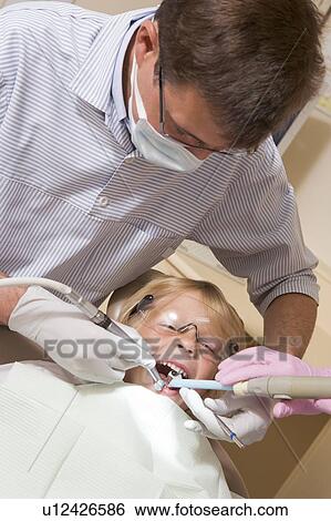Stock Photograph - Dentist in exam room with young boy in chair. Fotosearch