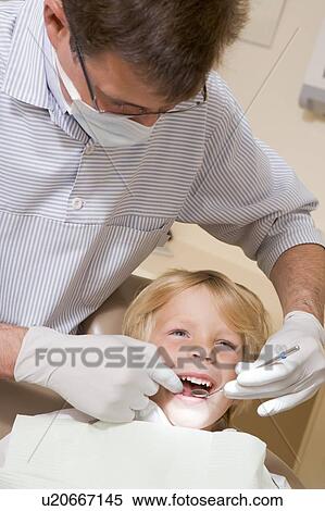 Stock Photography - Dentist in exam room with young boy in chair. Fotosearch
