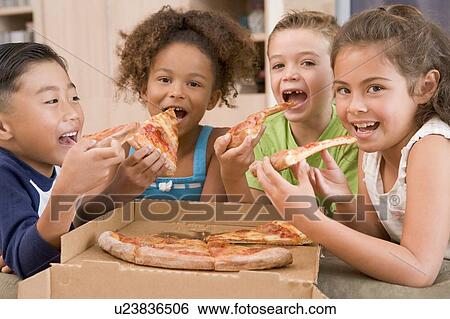 Stock Photograph - Four young children indoors eating pizza smiling. Fotosearch