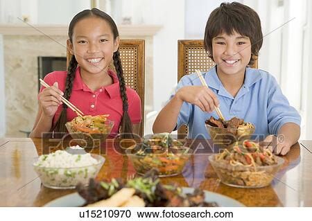 Two young children eating chinese food in dining room smiling View Large Photo Image Stock Image - Two young children eating chinese food in dining room smiling. Fotosearch