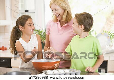 Woman and two children in kitchen baking and smiling View Large Photo Image Stock Photo - Woman and two children in kitchen baking and smiling. Fotosearch