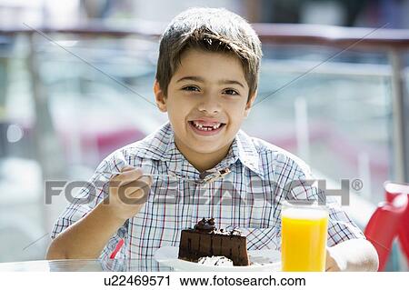 Young boy at restaurant eating dessert and smiling (selective focus) View Large Photo Image Stock Image - Young boy at restaurant eating dessert and smiling (selective focus). Fotosearch