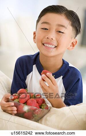 Young boy eating strawberries in living room smiling View Large Photo Image Stock Image - Young boy eating strawberries in living room smiling. Fotosearch