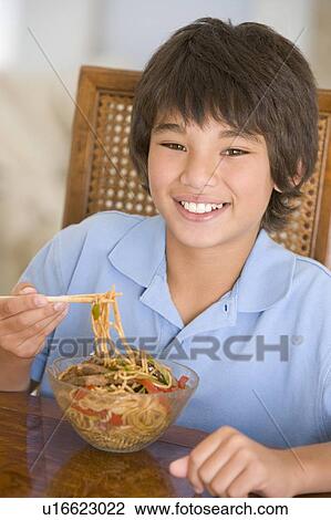 Young boy in dining room eating chinese food smiling View Large Photo Image Stock Image - Young boy in dining room eating chinese food smiling. Fotosearch