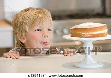 Young boy in kitchen looking at cake on counter View Large Photo Image Picture - Young boy in kitchen looking at cake on counter. Fotosearch