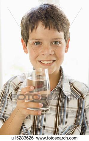 Stock Photograph - Young boy indoors drinking water smiling. Fotosearch