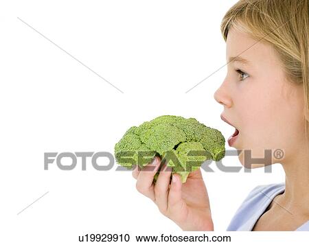 Stock Image - Young girl eating broccoli. Fotosearch