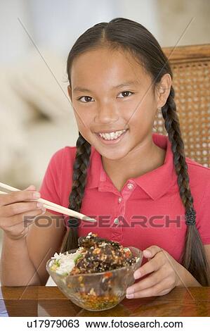 Young girl in dining room eating chinese food smiling View Large Photo Image Stock Image - Young girl in dining room eating chinese food smiling. Fotosearch