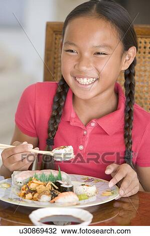 Young girl in dining room eating Chinese food smiling View Large Photo Image Stock Image - Young girl in dining room eating Chinese food smiling. Fotosearch