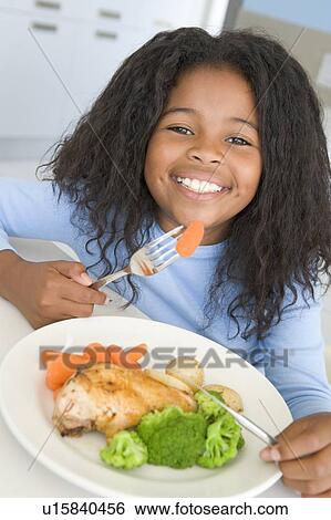 Young girl in kitchen eating chicken and vegetables smiling View Large Photo Image Stock Photograph - Young girl in kitchen eating chicken and vegetables smiling. Fotosearch