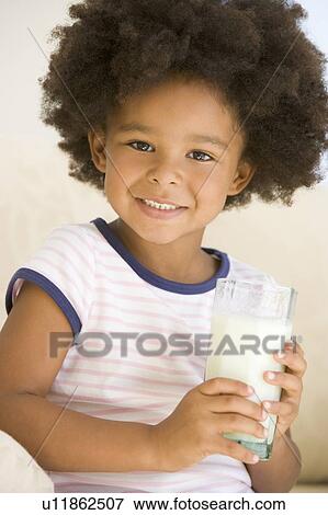 Stock Photo - Young girl indoors drinking milk smiling. Fotosearch