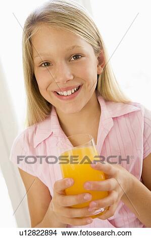 Young girl indoors drinking orange juice smiling View Large Photo Image Picture - Young girl indoors drinking orange juice smiling. Fotosearch