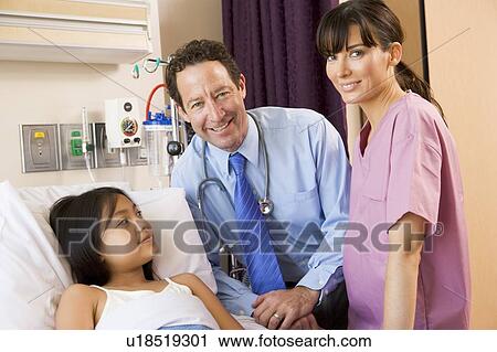Stock Image - Doctor And Nurse Standing In Hospital Room With Young Girl. Fotosearch
