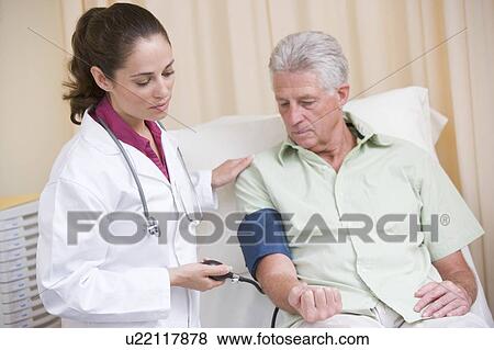 Doctor checking man's blood pressure in exam room View Large Photo Image Stock Photo - Doctor checking man's blood pressure in exam room. Fotosearch