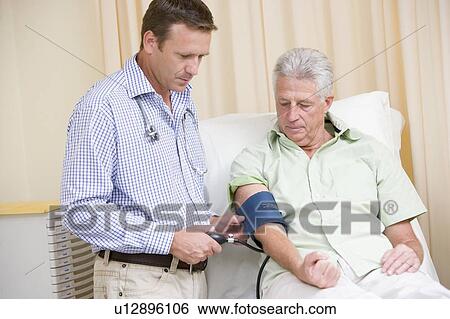Doctor checking man's blood pressure in exam room View Large Photo Image Stock Photograph - Doctor checking man's blood pressure in exam room. Fotosearch