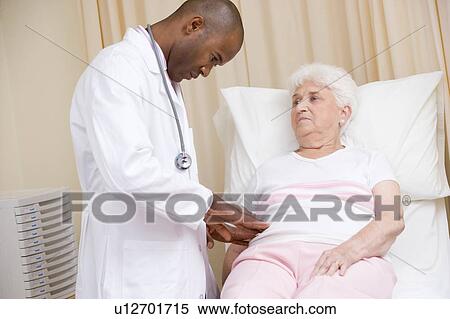 Stock Photography - Doctor giving checkup to woman in exam room. Fotosearch