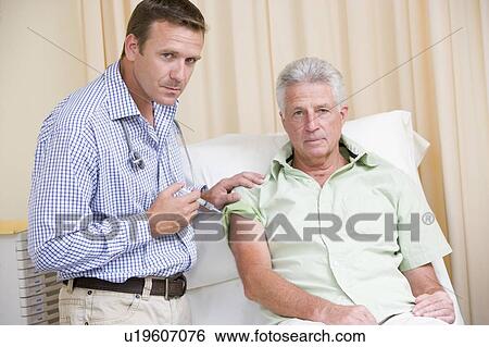 Doctor giving man needle in exam room View Large Photo Image Stock Photograph - Doctor giving man needle in exam room. Fotosearch