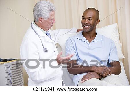 Stock Image - Doctor giving smiling man checkup in exam room. Fotosearch