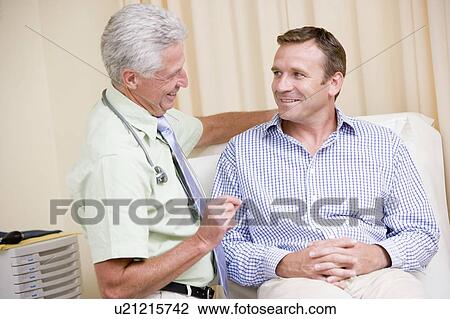 Doctor giving smiling man checkup in exam room View Large Photo Image Stock Image - Doctor giving smiling man checkup in exam room. Fotosearch