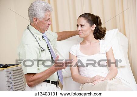 Stock Image - Doctor giving woman checkup in exam room. Fotosearch