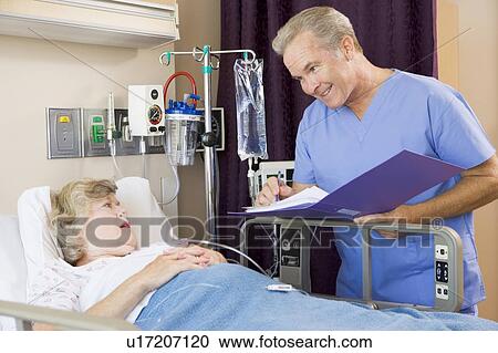 Stock Image - Doctor Making Notes About Senior Woman Patient. Fotosearch
