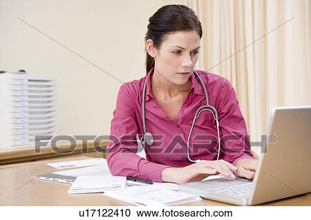 Stock Image - Doctor using laptop in doctor's office. Fotosearch