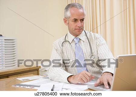 Stock Image - Doctor using laptop in doctor's office. Fotosearch