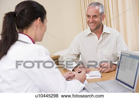 Doctor with laptop and man in doctor's office smiling View Large Photo Image Stock Photo - Doctor with laptop and man in doctor's office smiling. Fotosearch