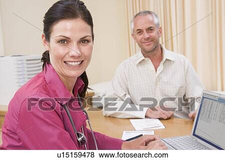 Stock Photo - Doctor with laptop and man in doctor's office smiling. Fotosearch