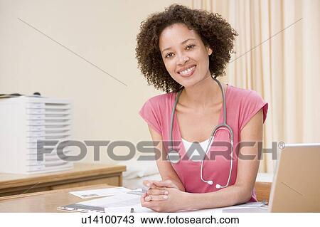 Doctor with laptop in doctor's office smiling View Large Photo Image Stock Image - Doctor with laptop in doctor's office smiling. Fotosearch