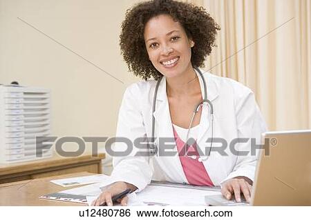 Doctor with laptop in doctor's office smiling View Large Photo Image Stock Photograph - Doctor with laptop in doctor's office smiling. Fotosearch